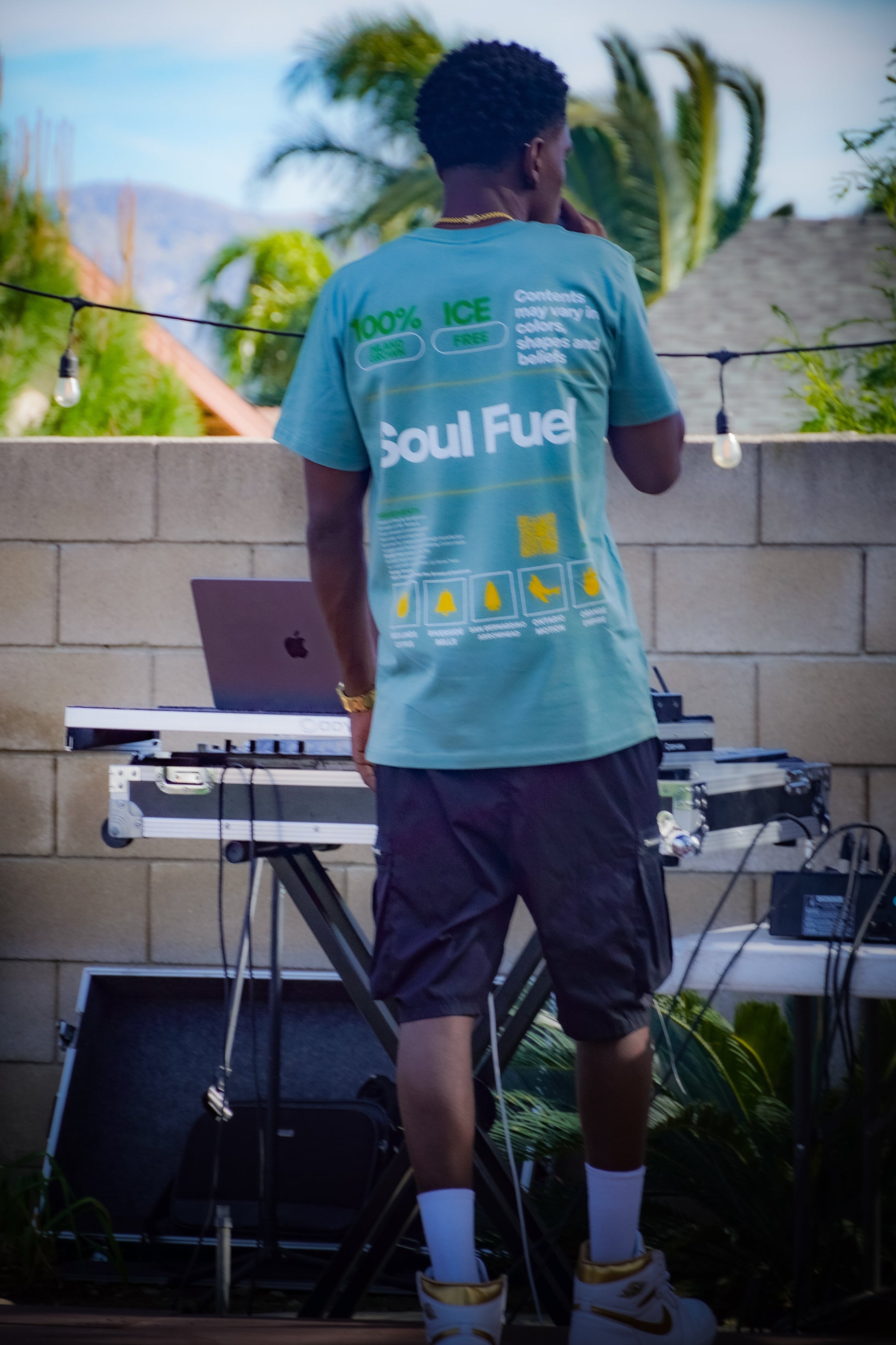 IE Native MillsWasChosen wearing a 'Soul Fuel' t-shirt standing outdoors with electronic equipment.